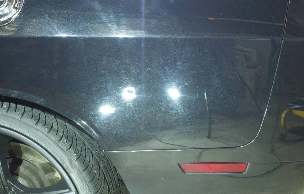 Swirl marks on a black Dodge Challenger under an inspection light